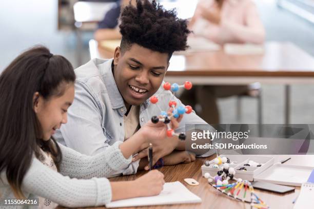 girl draws molecule while teen helps - teen tutor stock pictures, royalty-free photos & images