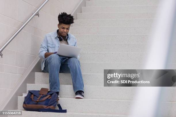 young adult male finds quiet place on stairs to study - boy library stock pictures, royalty-free photos & images