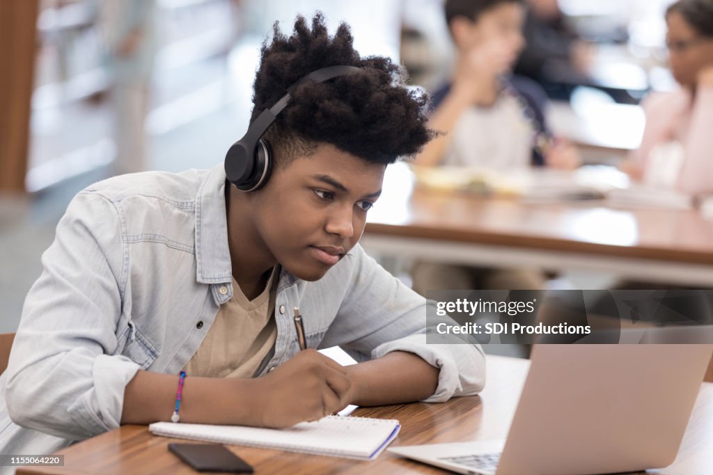 African American College student werkt aan onderzoek in de bibliotheek