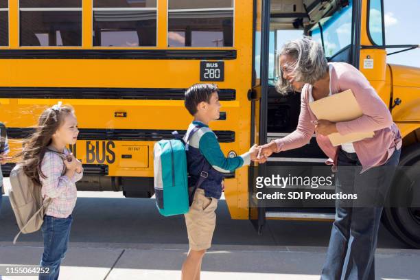 colegial sacude la mano de su nuevo conductor de autobús - reglas de sociedad fotografías e imágenes de stock
