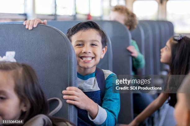 schoolboy smiles excitedly while sitting on school bus - school bus trip stock pictures, royalty-free photos & images