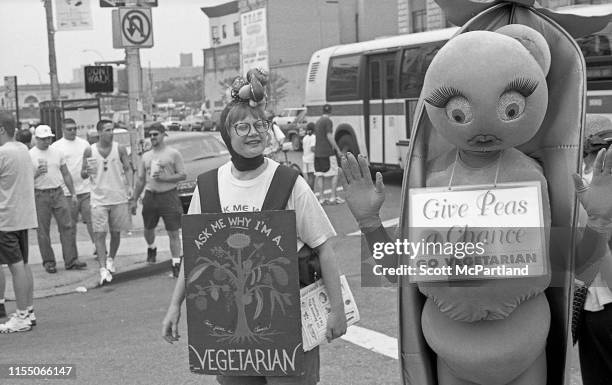 View of two pro-vegetarian activists, one with a sandwich board and the other dressed as pea pod, at the annual Nathan's Hot Dog Eating Contest at...