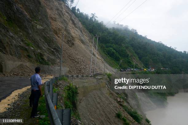 An Indian man stands along the national nighway 10 following a landslide due to heavy rainfall in the area, in Setijhora some 40 kms from Siliguri on...