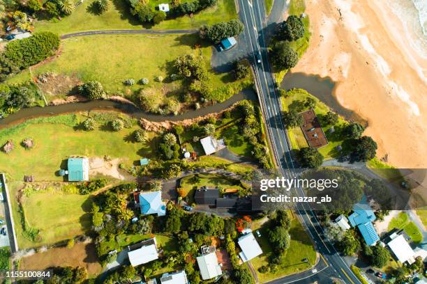looking down at houses and road along beach. - new zealand beach house stock pictures, royalty-free photos & images