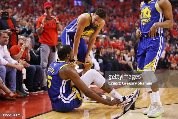 Klay Thompson of the Golden State Warriors helps Kevin Durant to his feet in the first half against the Toronto Raptors during Game Five of the 2019...