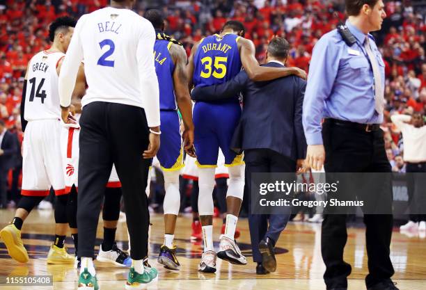 Kevin Durant of the Golden State Warriors is assisted off the court after sustaining an injury in the first half against the Toronto Raptors during...