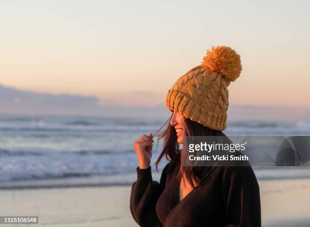 young asian lady dressed for winter on the beach - dawn australia stock pictures, royalty-free photos & images