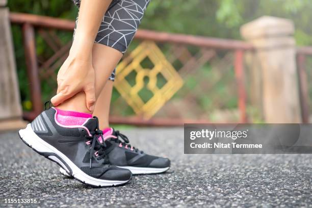 close-up asian woman standing on road holds her ankle injury after jogging - twisted ankle stock pictures, royalty-free photos & images