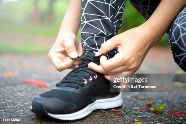 close-up young asian girl runner tying sport shoe before running in public park - marathon feet stock pictures, royalty-free photos & images