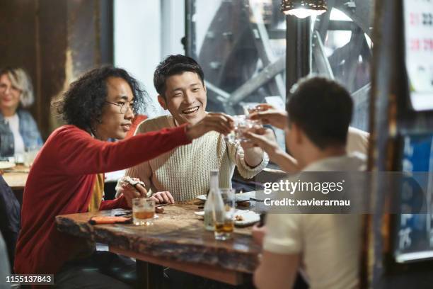 group of japanese male friends toasting with drinks after work - sake stock pictures, royalty-free photos & images