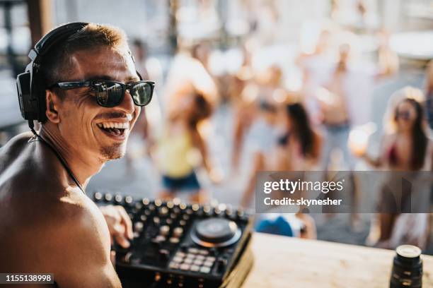 fröhlicher männlicher dj, der auf einer strandparty musik spielt. - headphones turntable stock-fotos und bilder