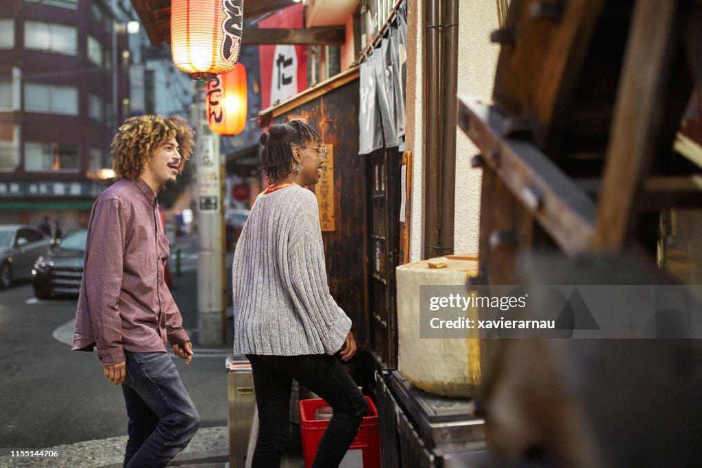 Coppia multietnica che entra nel ristorante Tokyo di notte