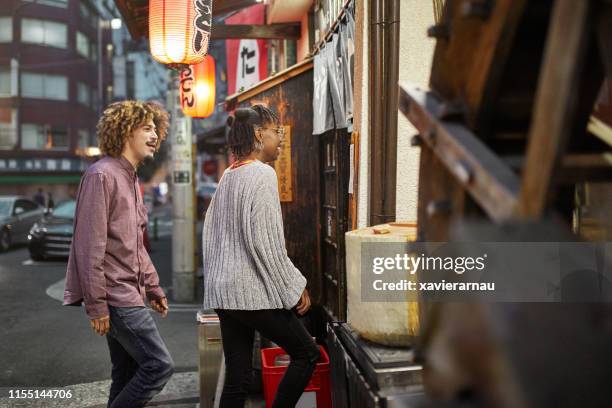 multi-ethnic couple entering tokyo restaurant at night - entering restaurant stock pictures, royalty-free photos & images