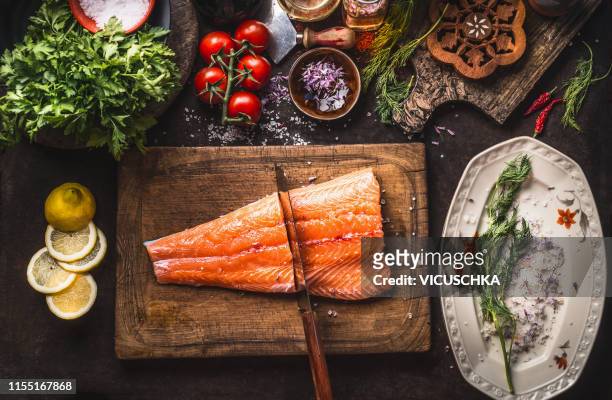 raw salmon half fish fillet on cutting board with knife and flavor ingredients - lachs stock-fotos und bilder
