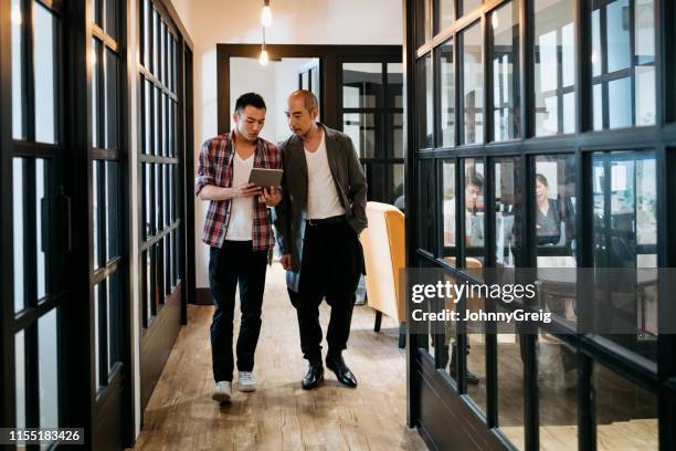 zakenlieden lopen langs de gang met digitale tablet - cool office stockfoto's en -beelden