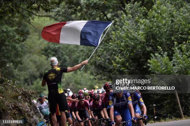 Cyclism enthusiast waves a French national flag as riders pass by during the sixth stage of the 106th edition of the Tour de France cycling race...