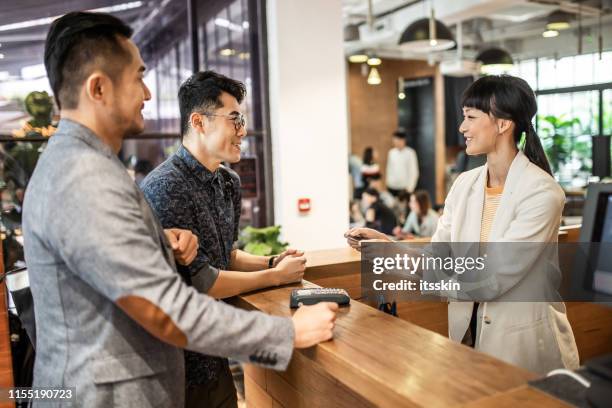 cardless paying at the reception. - asian receptionist stock pictures, royalty-free photos & images