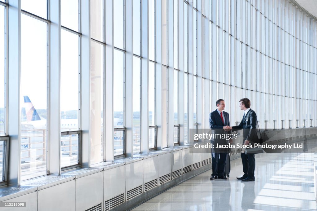 Caucasian businessmen shaking hands in airport