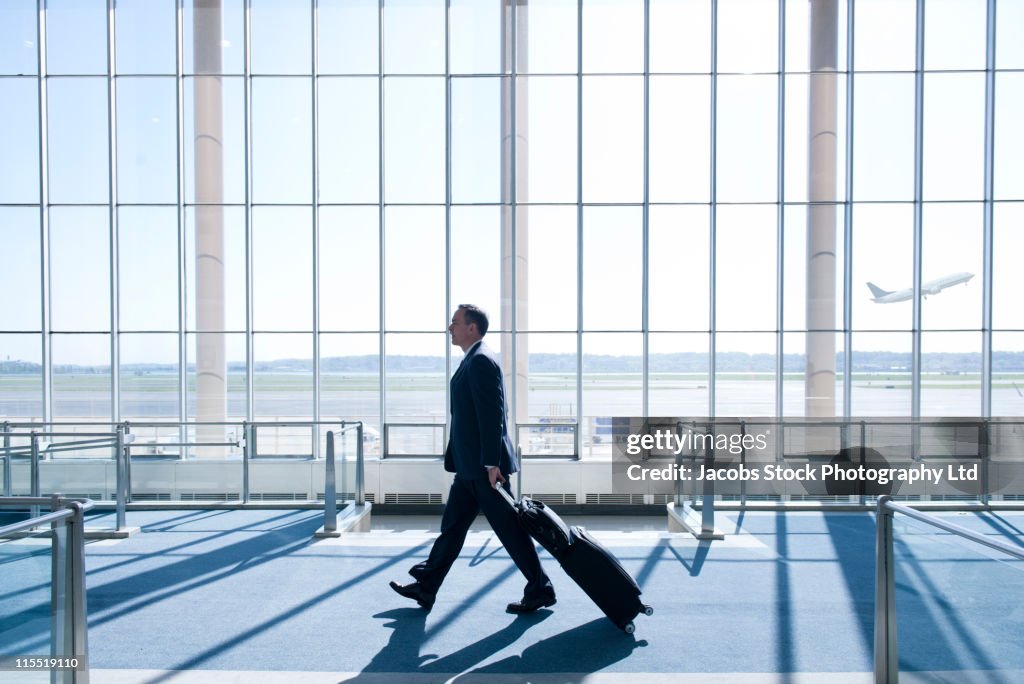 Caucasian businessman pulling luggage in airport