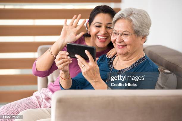 woman with senior mother using mobile phone for video chat - daughter in law stock pictures, royalty-free photos & images