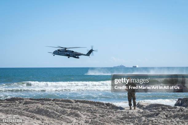 An US soldier looking at an helicopter flying near the water during the Amphibious Bold Alligator Exercise organized by the US Navy and the Marine...