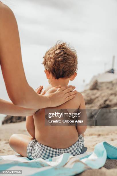 mother applying sunscreen to her child - human skin back stock pictures, royalty-free photos & images