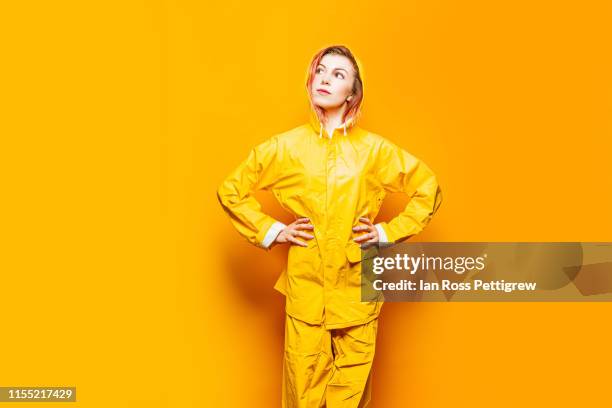 cute young woman wearing yellow raincoat and pants - raincoat stockfoto's en -beelden