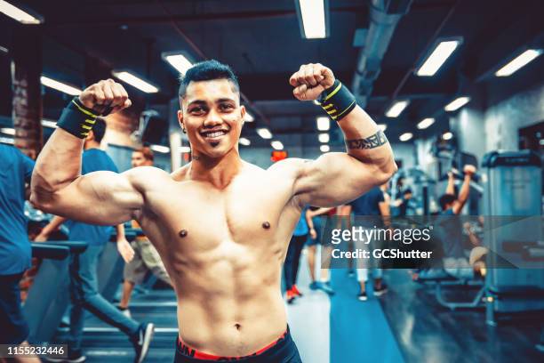 homme adulte asiatique montrant ses muscles dans un centre de remise en forme - asian six pack photos et images de collection