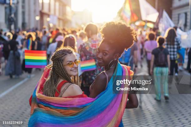 schönes weibliches paar mit regenbogenschal zu fuß mit dem stolz festival - pride fest stock-fotos und bilder