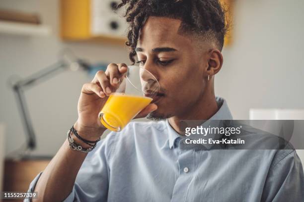 junger mann zu hause - orange juice stock-fotos und bilder
