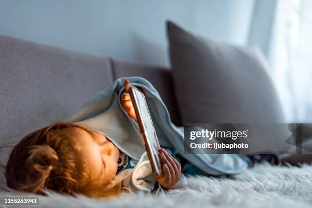 baby jongen in bed sms'en op smartphone - under sofa stockfoto's en -beelden