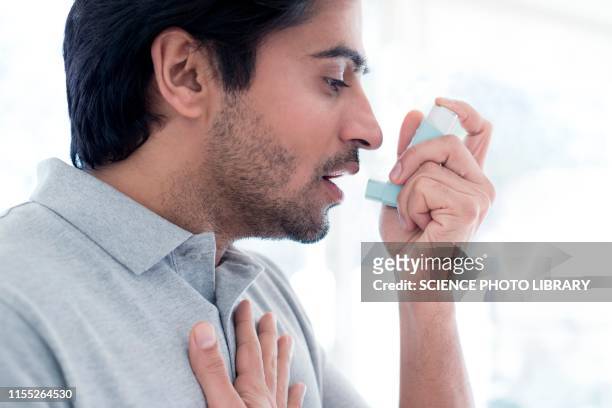 man using inhaler - asmático fotografías e imágenes de stock