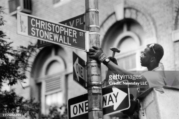 Traffic device worker Darryl Beckles changes the street sign on Christopher Street in Greenwich Village in Manhattan to Christopher Street/Stonewall...