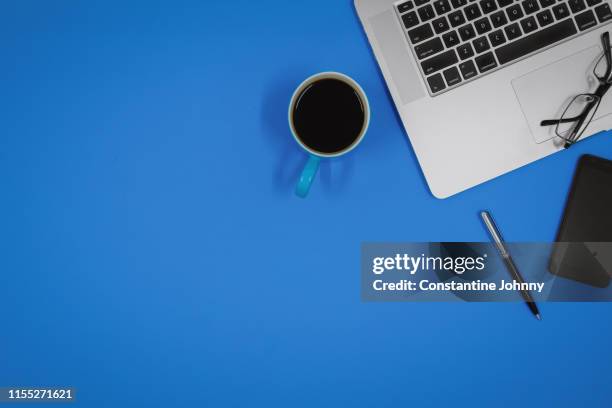 laptop and coffee mud on blue work desk - office work flat lay stock-fotos und bilder