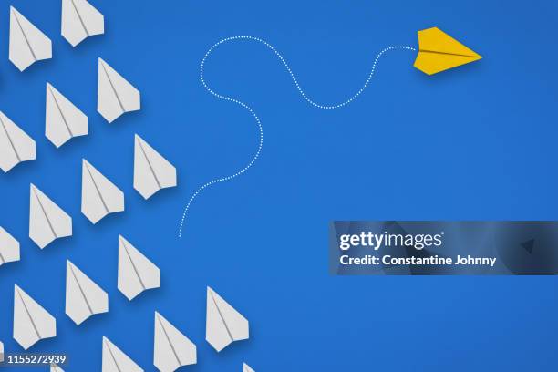 group of paper airplanes in same direction and one airplane moving to different direction. think different concept. - same action stock-fotos und bilder