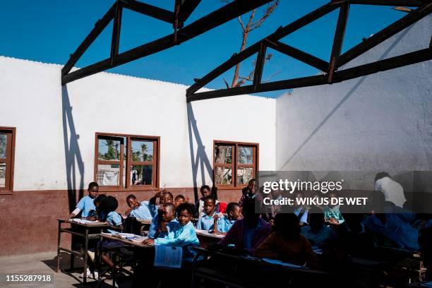 Children sit in a classroom at the Escola 25 de Juhno in Munhava district that was damaged during Cyclone Idai, on July 12, 2019 in Beira. -...