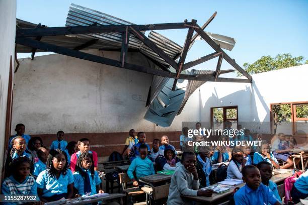 Children sit in a classroom at the Escola 25 de Juhno in Munhava district that was damaged during Cyclone Idai, on July 12, 2019 in Beira. -...