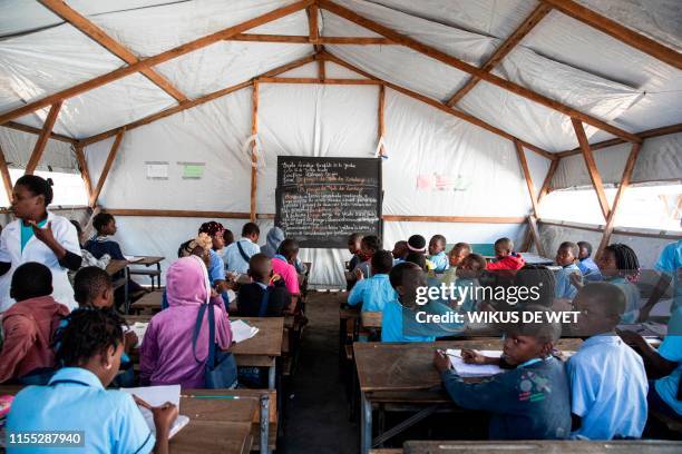 Children sit in a classroom at the Escola 25 de Juhno in Munhava district that was damaged during Cyclone Idai, on July 12, 2019 in Beira. -...