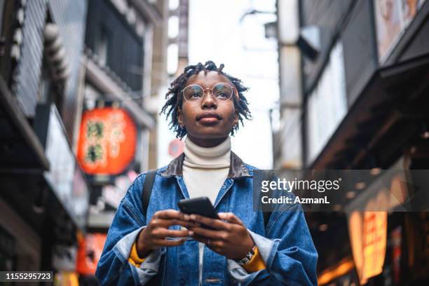donna africana con smartphone in vacanza a tokyo - japanese culture foto e immagini stock