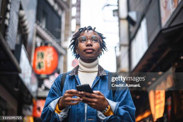 afrikansk kvinna med smartphone vacationing i tokyo - woman looking up bildbanksfoton och bilder