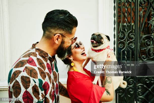 laughing woman holding up dog while walking through town with boyfriend - americas next top dog fotografías e imágenes de stock