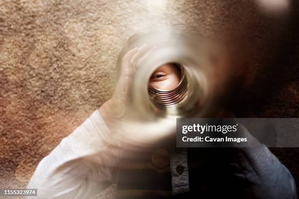 a small boy playing with a slinky in the camera lens - metal coil toy stockfoto's en -beelden