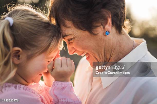 close up of grandmother and granddaughter looking at each other and la - grandmother granddaughter stock pictures, royalty-free photos & images