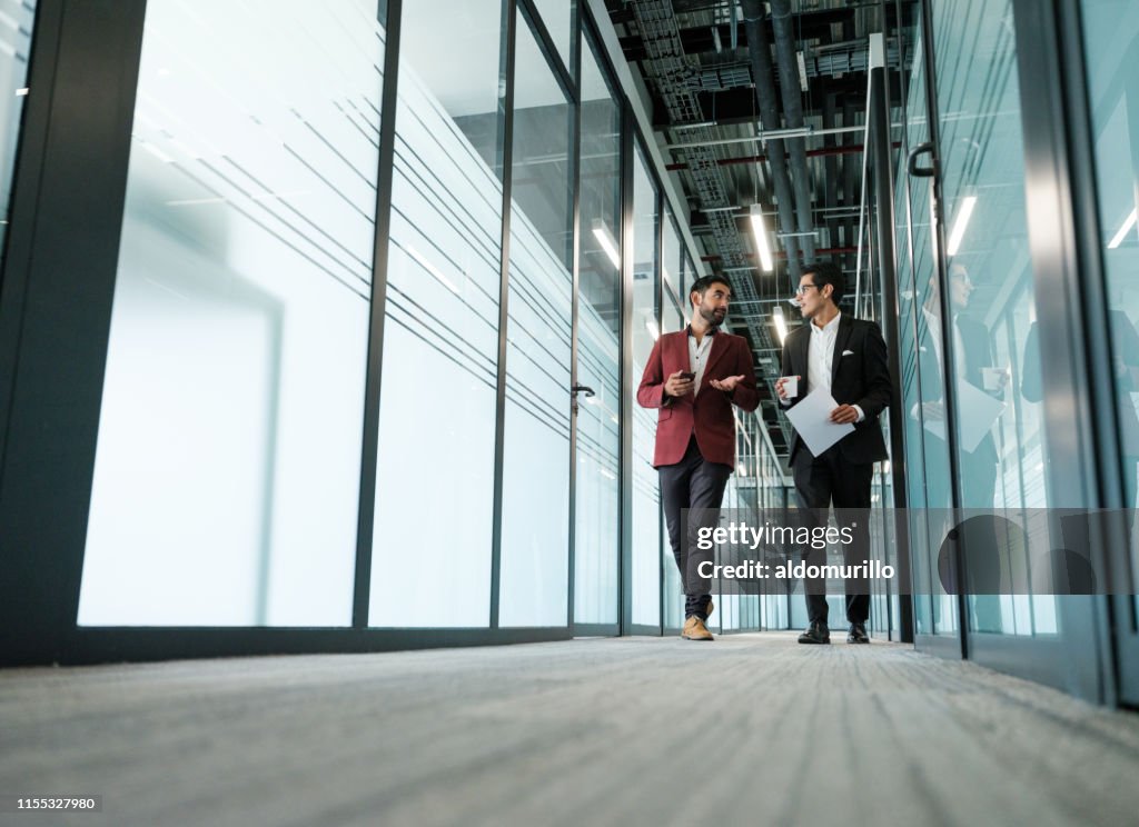 Corporate men walking in a building while discussing work