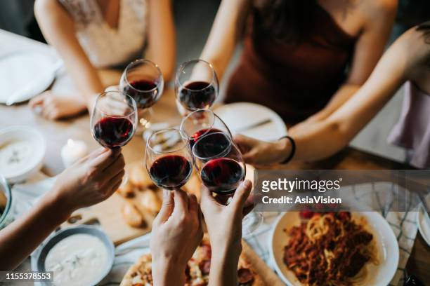 nahaufnahme von glücklichen jungen freunden mit spaß und toasten und feiern mit rotwein während der party - warmes abendessen stock-fotos und bilder