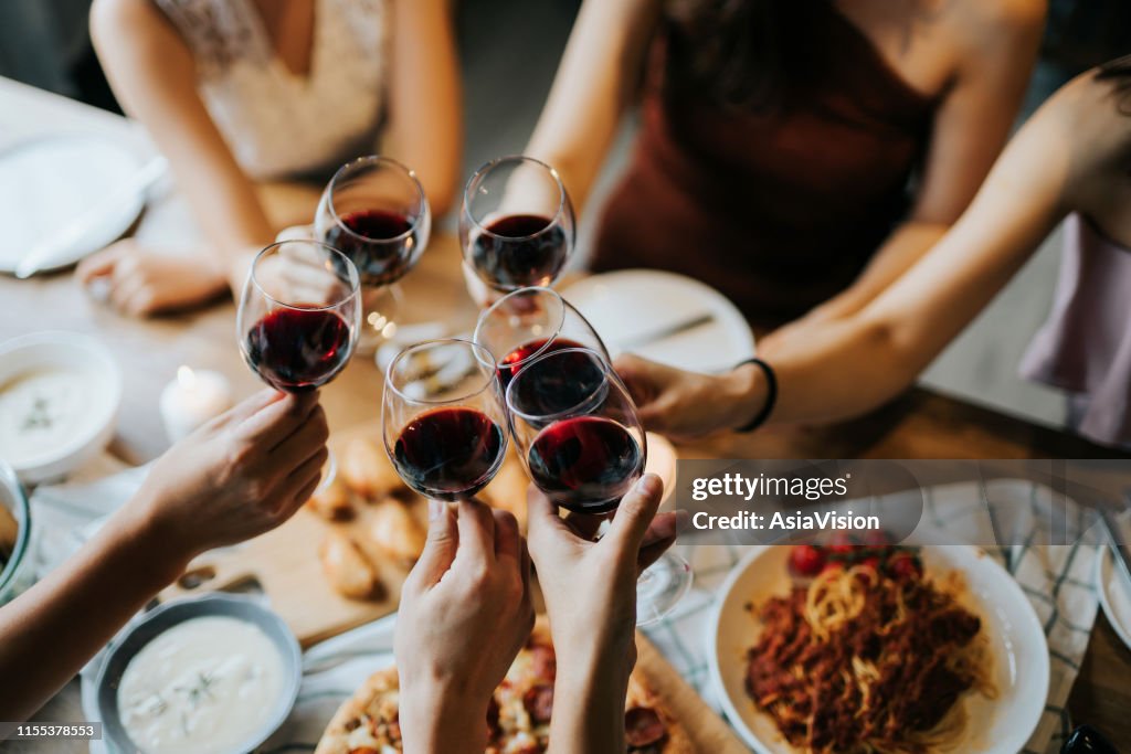 Close-up van gelukkige jonge vrienden met plezier en toasten en vieren met rode wijn tijdens de partij