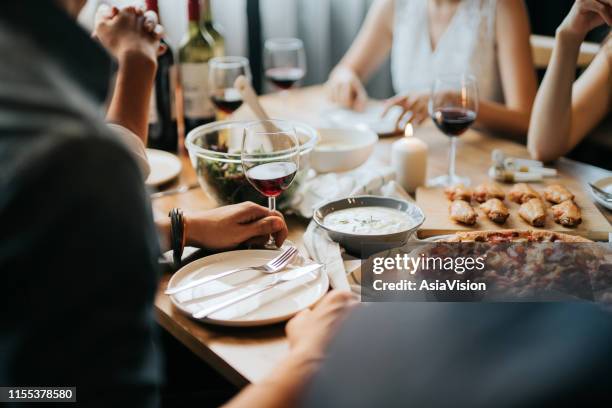 group of joyful young asian man and woman having fun, enjoying food and wine across table during party - group of people eating dinner stock pictures, royalty-free photos & images