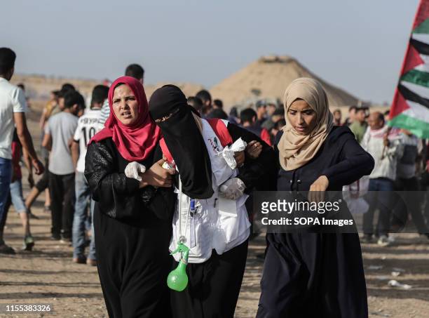 Palestinian demonstrators help a medic suffering from exposure to tear gas during Clashes while demonstrating demanding an end to the Israeli...