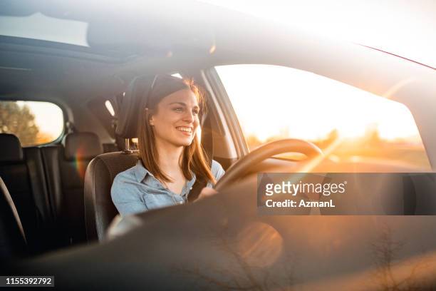 mujer joven conduciendo coche en un día soleado - coche fotografías e imágenes de stock