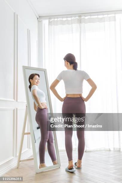 woman checking her body through mirror - full length mirror fotografías e imágenes de stock